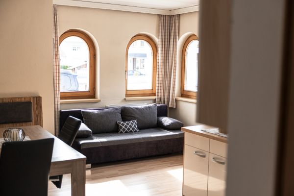 Gemütlicher Wohnbereich mit Sofa und traditionellen Rundbogenfenstern im Apartment Grubigstein Gemütlicher Wohnbereich mit Sofa und traditionellen Rundbogenfenstern im Apartment Grubigstein